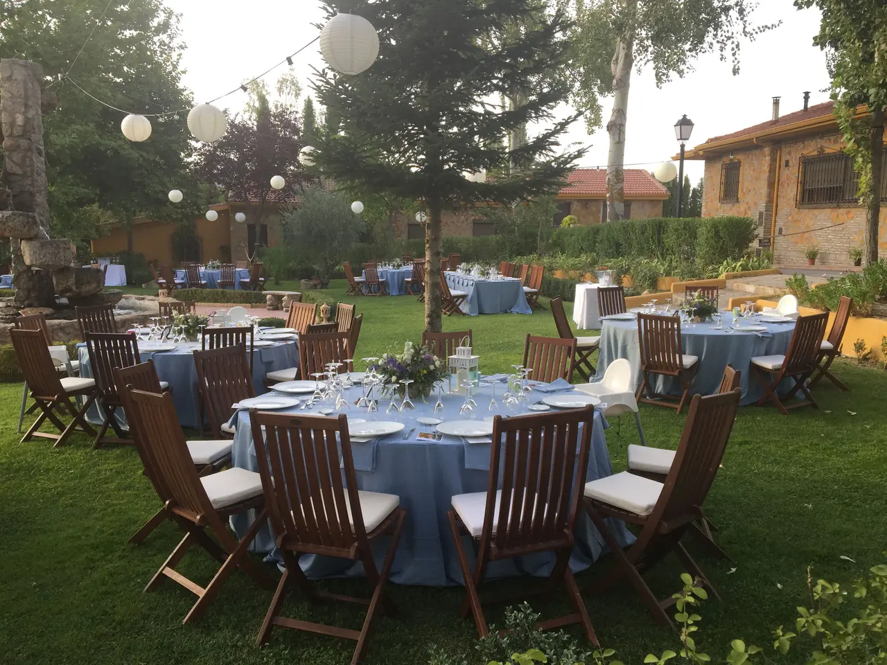 Mesas con mantel azul en el jardín, junto a la casa
