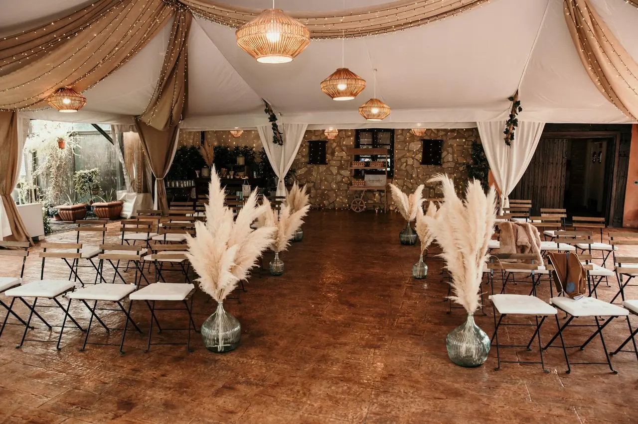 Carpa preparada para la ceremonia con pampas y sillas plegables