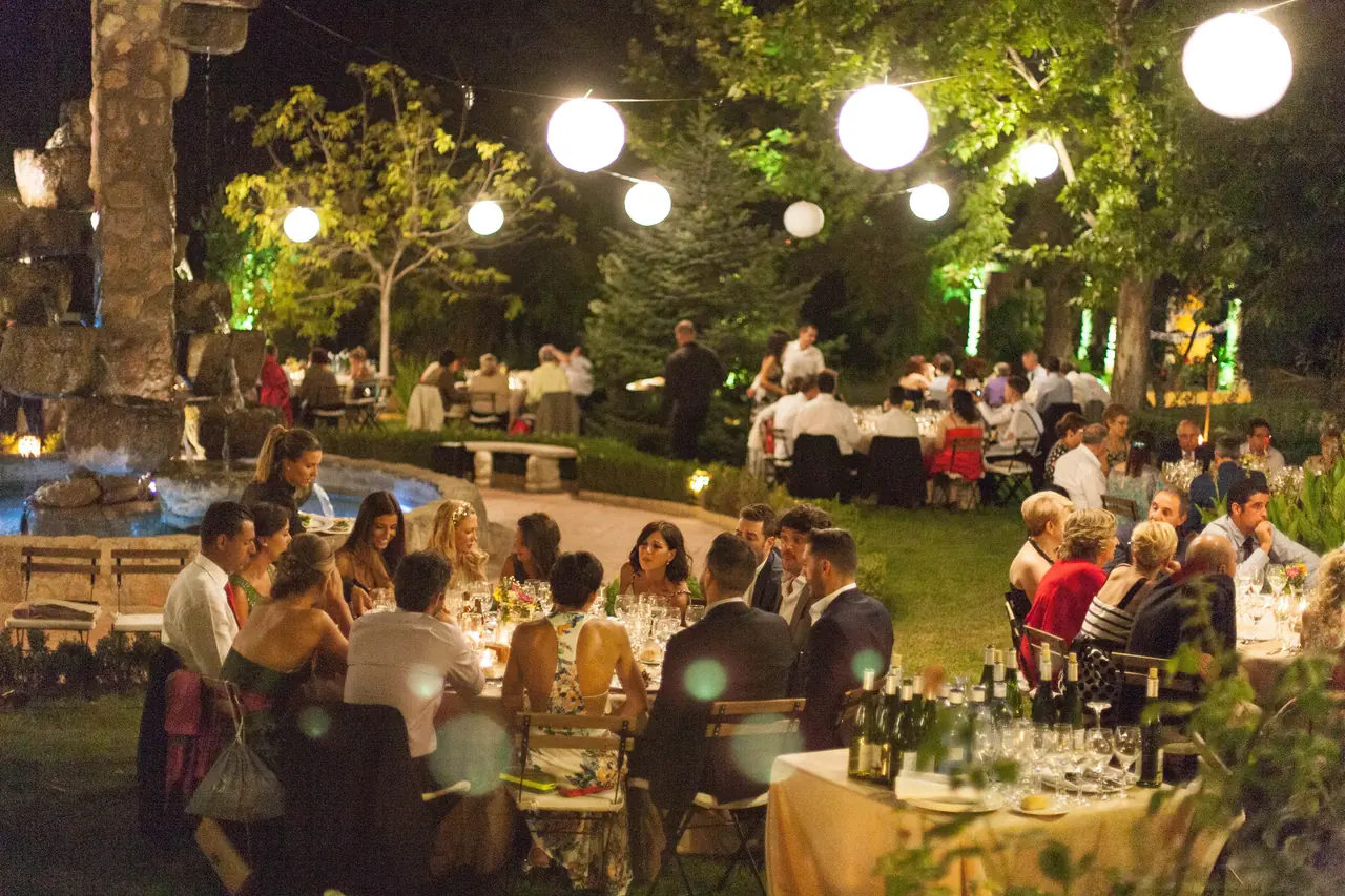 Cena de noche junto a la fuente, con farolillos encendidos sobre las mesas