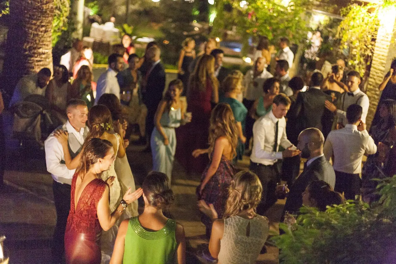 Invitados bailando de noche en el jardín