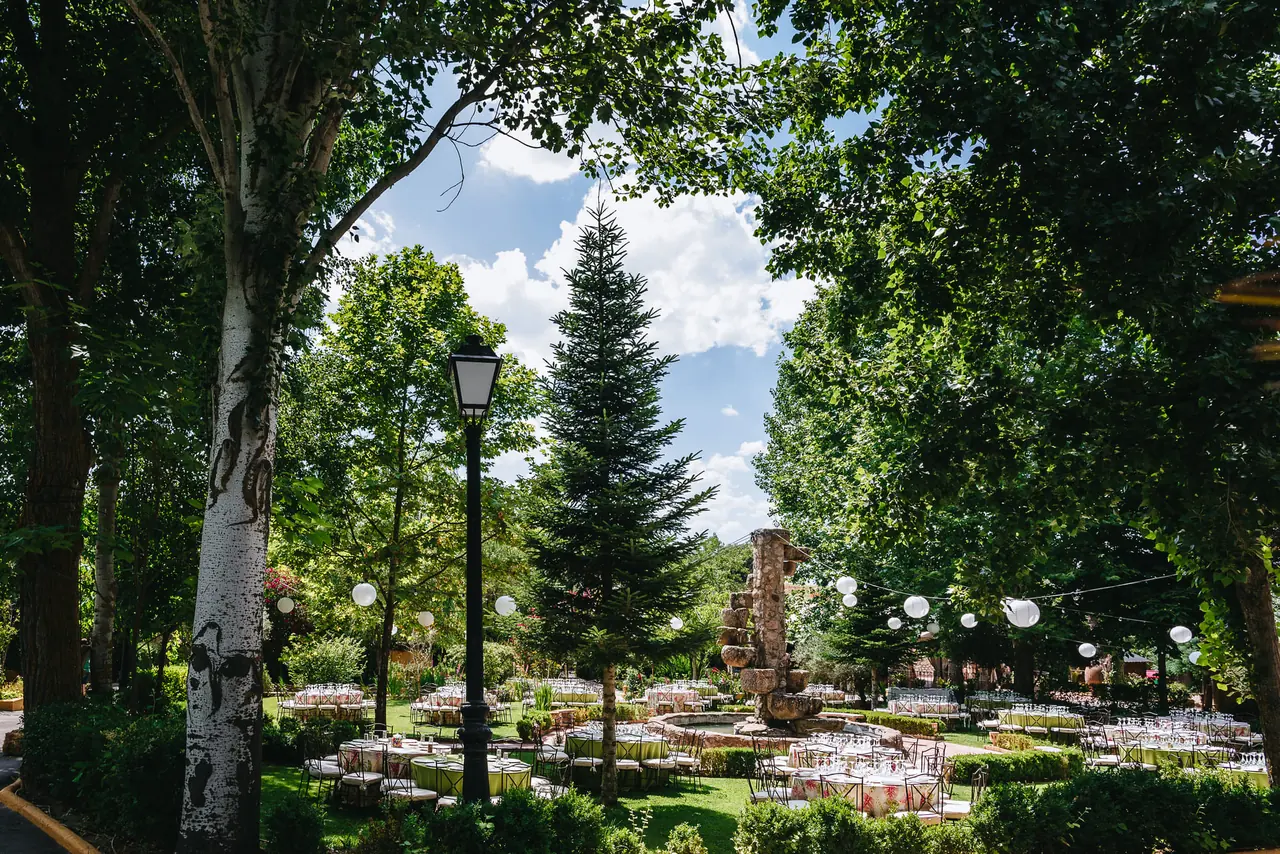 Mesas bajo los árboles altos del jardín