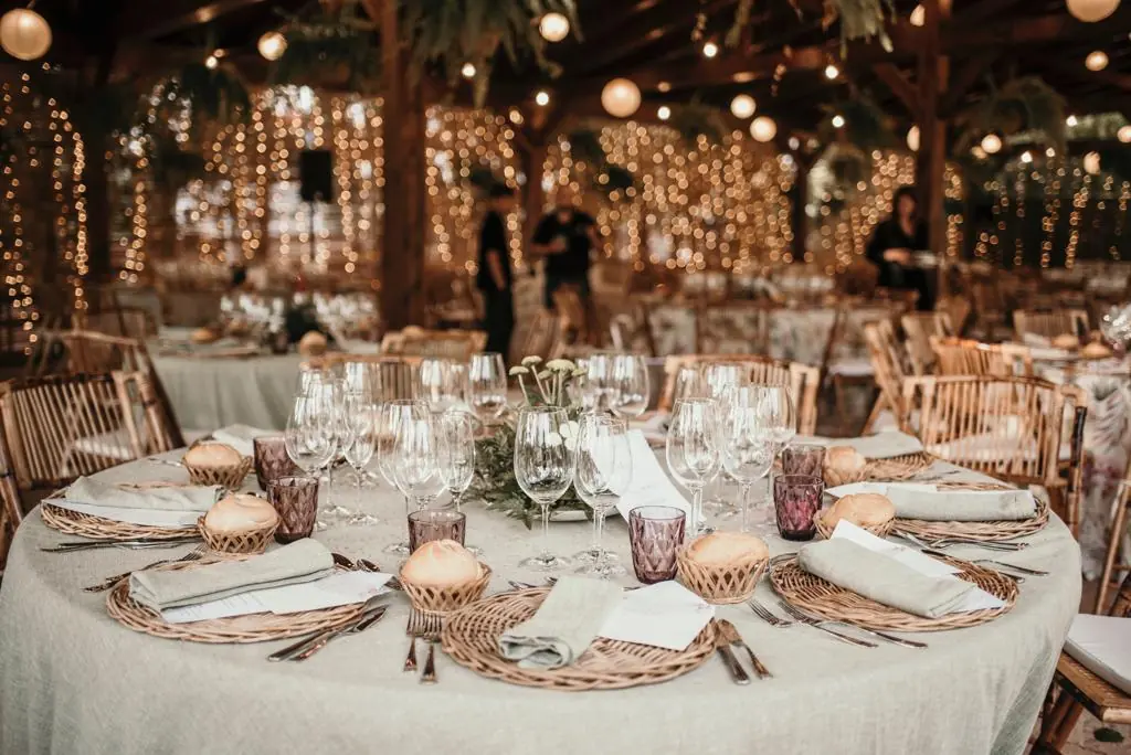 Mesa vestida con lino, mimbre y velas bajo las luces