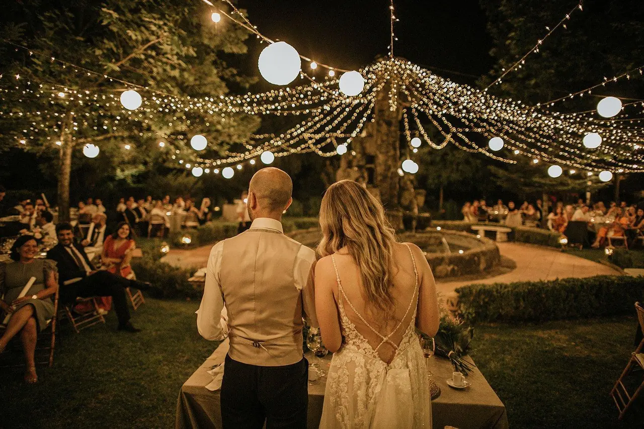 Novios de espaldas frente a sus invitados durante la cena