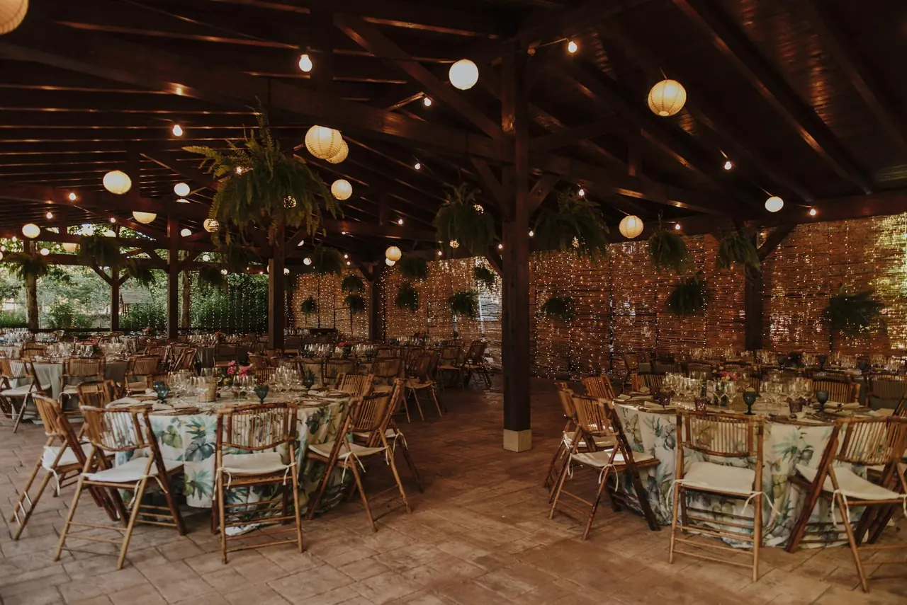Pérgola de madera con farolillos y mesas montadas