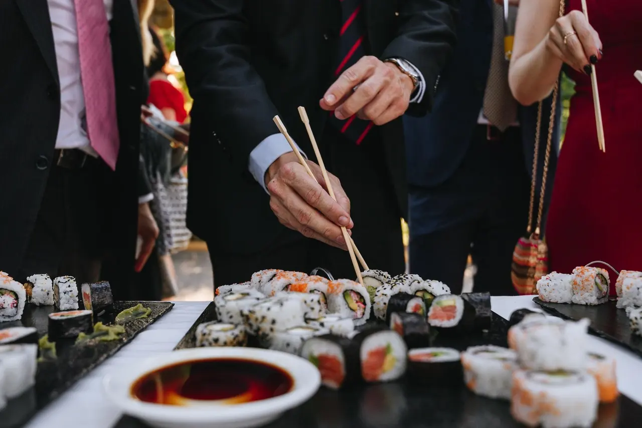 Invitados sirviéndose en el puesto de sushi del cóctel